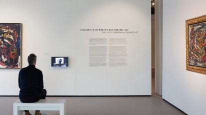 mijnheer zit voor een schilderij in het cobramuseum
